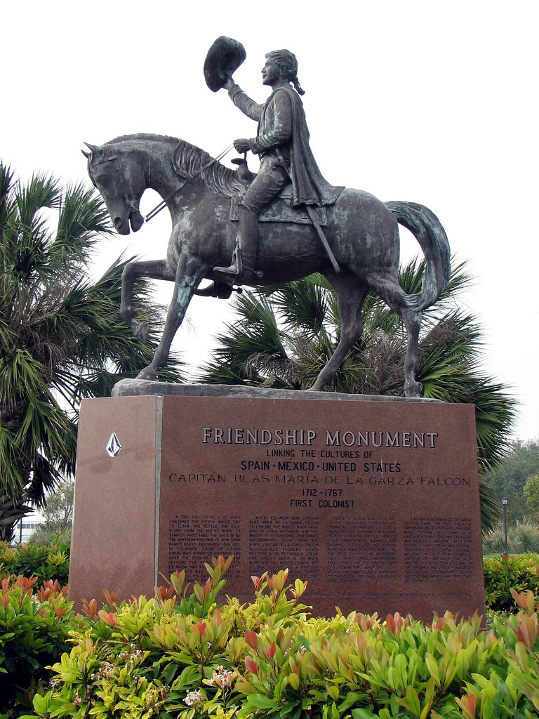 A statue of Captain Blas María de la Garza Falcón on his horse, lifting his hat in the air with one hand in a welcoming manner. The base of the statue reads, “Friendship Monument. Linking the cultures of Spain, Mexico, and the United States. Captain Blas María de la Garza Falcón: 1712-1767, First Colonist.” The Monument is in Corpus Christi, Texas.